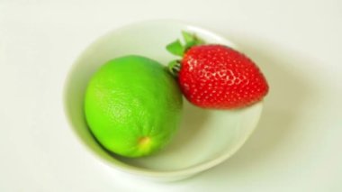 Limon meyve ve olgun çilek beyaz bir plaka üzerinde bir daire içinde döndürür. Yukarıdan görüntülemek