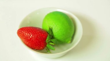 Limon meyve ve olgun çilek beyaz bir plaka üzerinde bir daire içinde döndürür. Yukarıdan görüntülemek