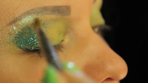 Una donna con un pennello si mette l'occhio coperto di ombre verdi succose scintille verdi — Video Stock