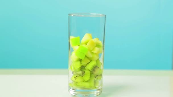 In a prozachny glass glass slices of fruit of a kiwi and apple are cut. Glass rotates in a circle. — Stock Video