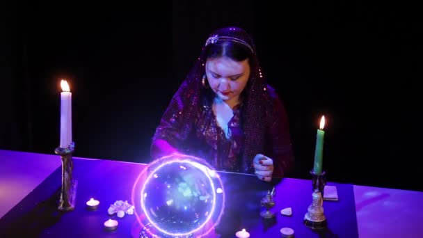 Цыганка читает будущее за камнями в свете волшебного шара молнии — стоковое видео