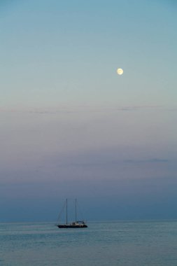 Akşam alacakaranlıkta denizde küçük bir Yelkenli.