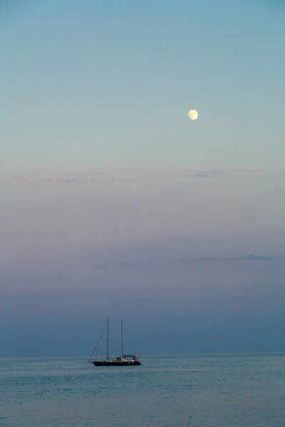 A small sailboat in the sea at dusk in the evening.