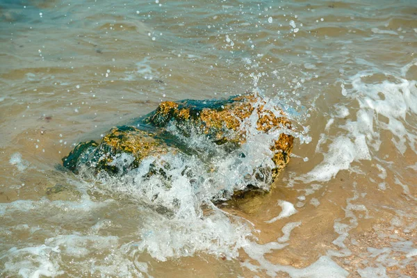 Stänk våg kraschar mot stenar på stranden med spray. — Stockfoto