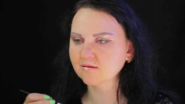 Brunette vrouw maakt lip make-up met felle gouden sparkles. Tijd ronden. — Stockvideo