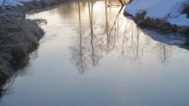 Baharda erken şafakta nehire. Yükselen güneş suya yansıtılır