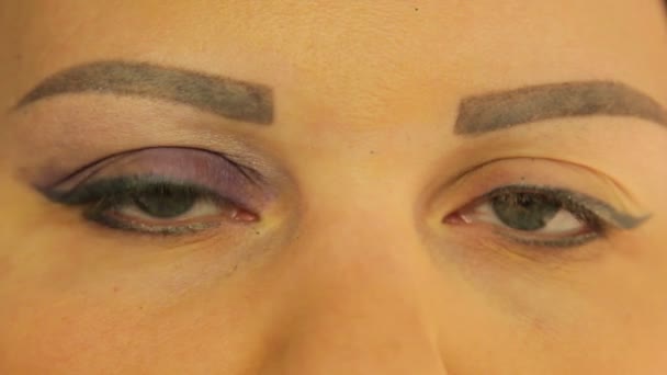 Female eyes one eye dyed with dark purple shadows — Stock Video