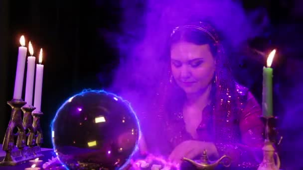 A young gypsy performs magical rituals over a ball of fire and glowing stones — Stock Video