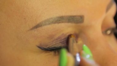 Bir fırça ile el göz makyajı koyu mor gölgeler ile yapar