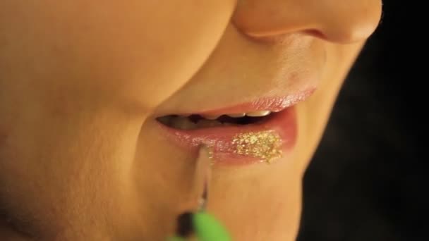 Una mano femminile condivide il suo trucco labbro con scintille d'oro . — Video Stock