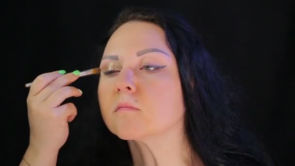 En brunett kvinna med ljusa gyllene gnistrar på hennes ögonlock. Tid varv — Stockvideo