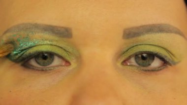 Kadın gözleri parlak yeşil gölgelerle boyanmıştır. Bir gözle, bir kadın sulu yeşil parıldayları koyar