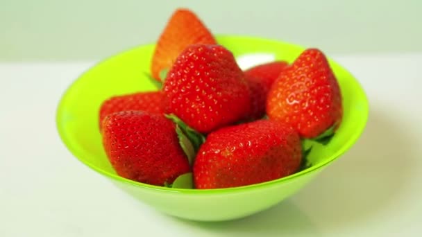 Red fresh strawberry berries in a green plate on a blue background rotate in a circle — Stock Video