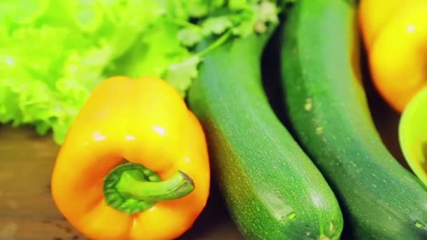 Auf dem Holztisch liegen frisches Gemüse Zucchini, Brokkoli, Salat, Avocado, Gurken, Paprika und Chili, Kirschtomaten — Stockvideo