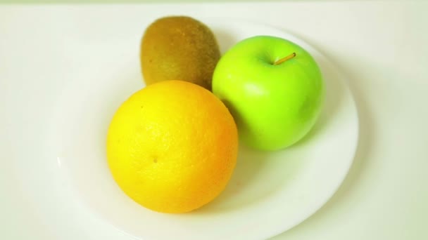 Orange Kiwi Och Grönt Äpple Vit Tallrik Roterar Cirkel Närbild — Stockvideo