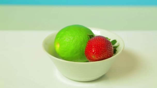 Fruits à la chaux et fraises mûres sur une assiette blanche tourne en cercle . — Video