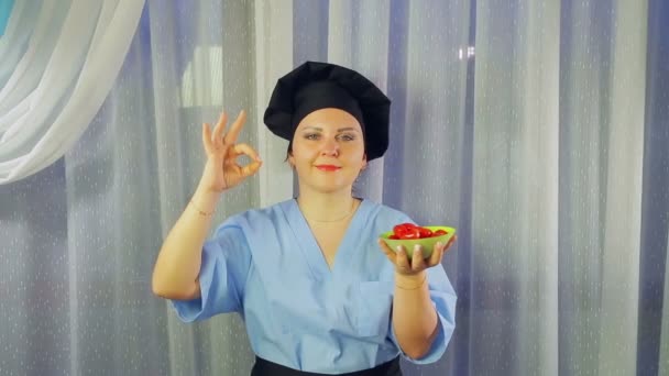 妇女在围裙微笑中做饭 手里拿着绿色沙拉 并展示手 平均计划 — 图库视频影像