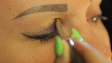 Bir fırça ile kadın el koyu mor gölge ile göz makyajı yapar
