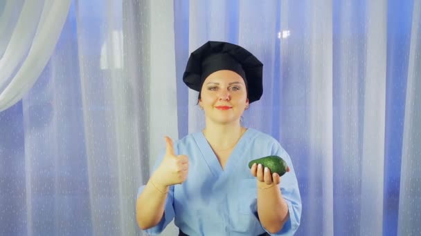 Eine Köchin lächelt, hält eine Avocado in der Hand und zeigt die Klasse — Stockvideo