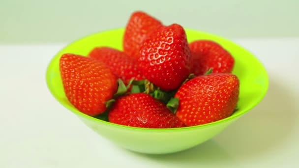 Red fresh strawberries in a green plate on a blue background rotate in a circle — Stock Video