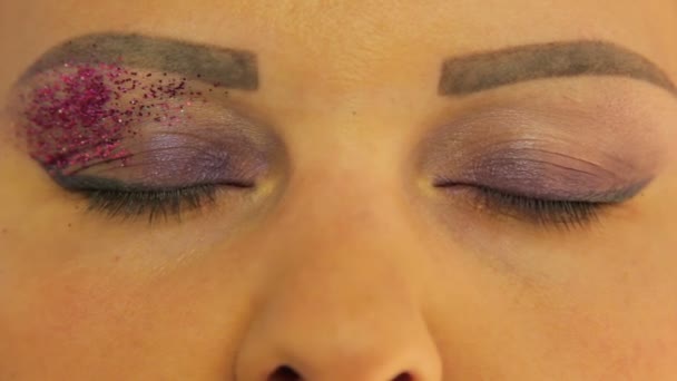 Női szemek egy lila make-up az egyik szeme fényes lila ragyog — Stock videók