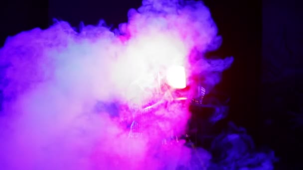 Una joven iluminadora en el escenario trabajando con un proyector de perfil teatral induce la luz en las nubes de humo . — Vídeos de Stock