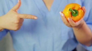 Kadın ellerinde sarı biber. Bir el onu işaret ediyor..