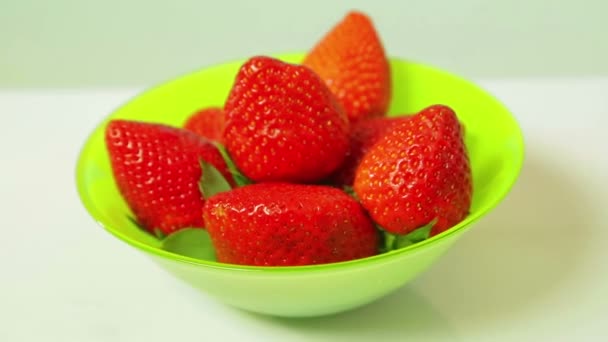 Red fresh strawberries in a green plate on a blue background rotate in a circle — Stock Video