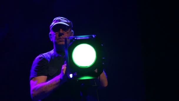 Een man illuminator op het podium werkt met een theater Profiel projector in een wolk van rook — Stockvideo