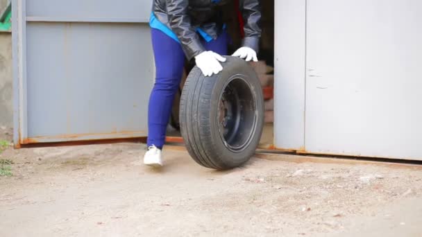 Manos femeninas extendiendo un neumático de coche con un disco fuera del garaje — Vídeo de stock