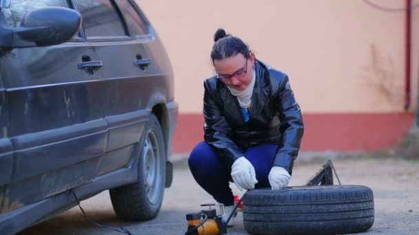 Женщина в перчатках качает автомобильную шину компрессором — стоковое видео