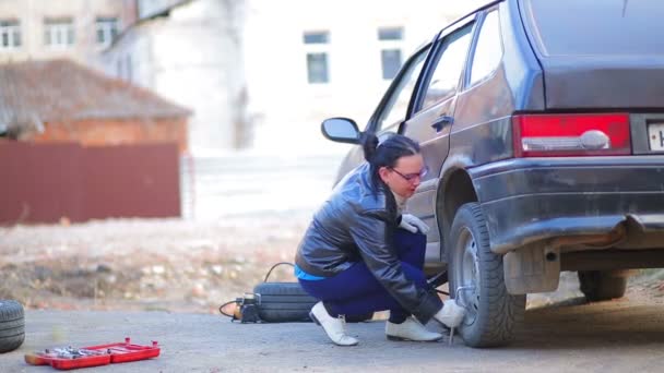 Eine Frau in Handschuhen mit einem Schraubenschlüssel schraubt die Muttern am Steuer eines Autos ab. — Stockvideo