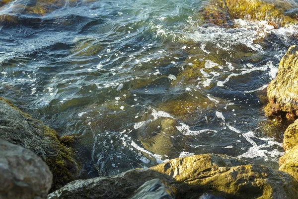 The wreckage of rocks in the sea near the rocky shore in the sea foam. — Stock Photo, Image