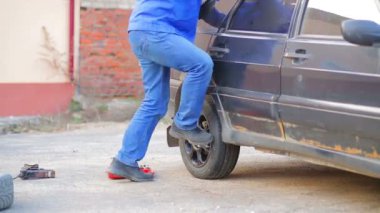 Bir anahtar ile erkek oto tamircisi bir araba tekerleği güvenli