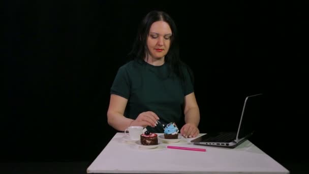Una mujer morena en una mesa en un café bebe café y come un pastel de postre — Vídeos de Stock