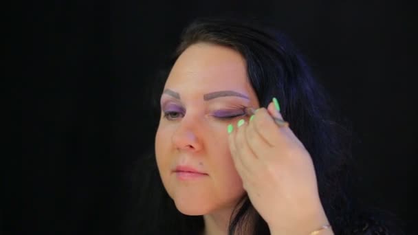 Женщина кладет на глаза кистью темно-фиолетовых теней — стоковое видео