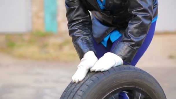 Womens hands rolling on the asphalt car tire with the disk — 비디오