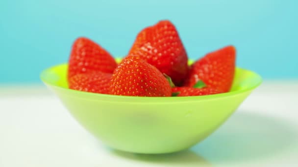 Las fresas maduras jugosas en el plato verde sobre el fondo azul giran en el círculo — Vídeo de stock