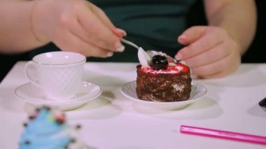 Kadınlar bir bardak kahve için kafenin siyah arka planına uzanır. Bir fincan kahve ve tatlı ile bir kaşık alır.