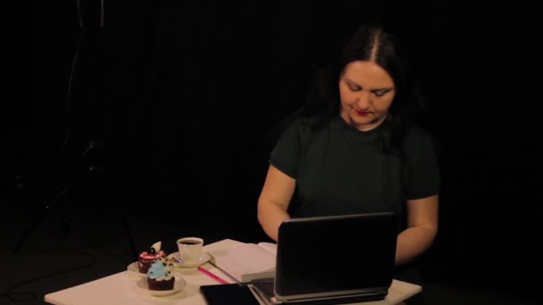 Eine Frau an einem Tisch in einem Café arbeitet am Computer und trinkt Kaffee — Stockvideo