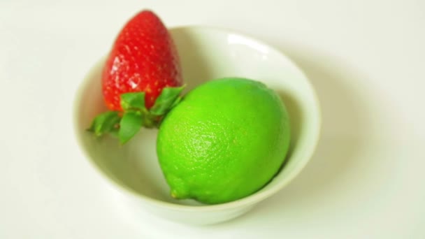 Limettenfrüchte und reife Erdbeeren auf einem weißen Teller drehen sich im Kreis. Blick von oben — Stockvideo