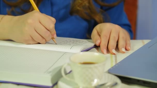 Női kezek a kávézóban az asztalnál, amit a naplójukba írnak. — Stock videók