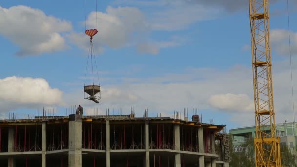 Construction work with rooftop workers and a tower crane raising construction materials — Stock Video
