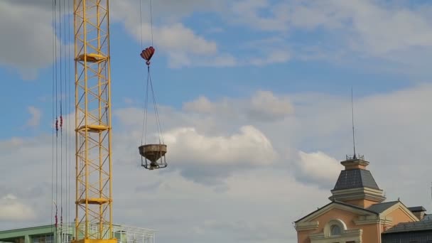 Torenkraan verhoogt en verlaagt materialen voor bouwwerkzaamheden aan het gebouw — Stockvideo