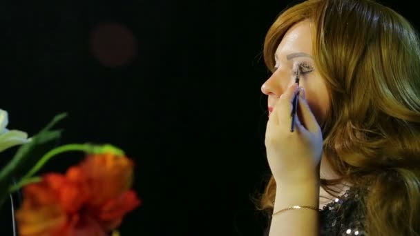 Atriz de cabelos vermelhos no camarim faz maquiagem para os olhos com brilhos pretos se preparando para subir ao palco — Vídeo de Stock