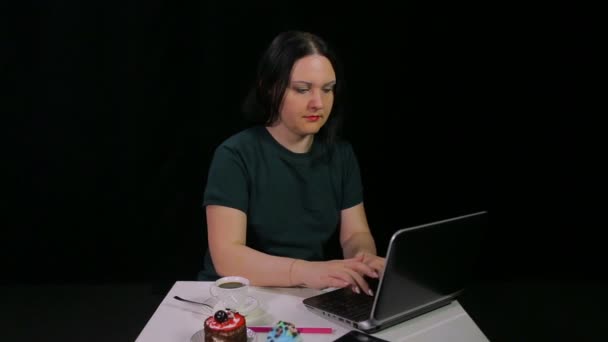 Ein brünettes Mädchen in einem Café arbeitet mit einem Computer und trinkt Kaffee in einem Café — Stockvideo