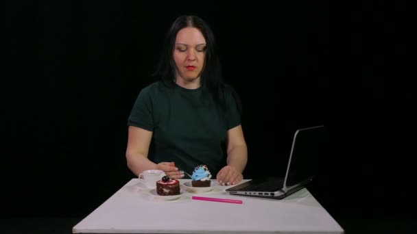 Eine brünette Frau an einem Tisch in einem Café trinkt Kaffee und isst einen Kuchen — Stockvideo