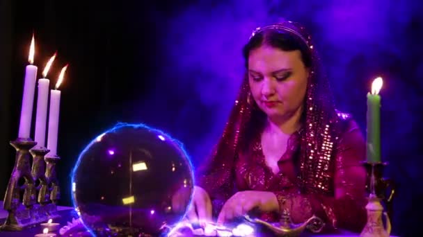 Eine Zigeunerin im magichsky-Salon wundert sich über weiße Steine und ein Bitcoin-Zeichen erscheint in der Kristallkugel — Stockvideo