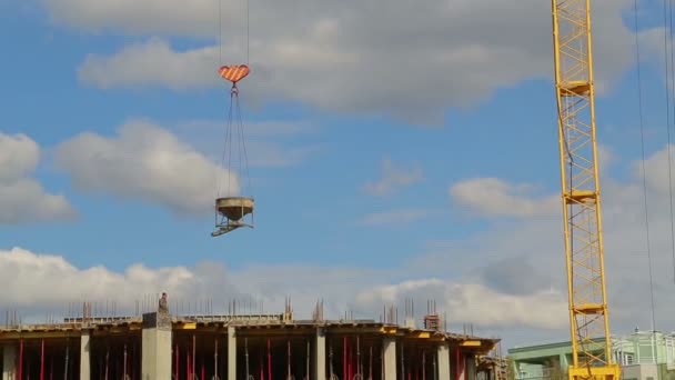 Kule vinç yükseltir ve bina üzerinde inşaat çalışmaları için malzeme düşürür — Stok video