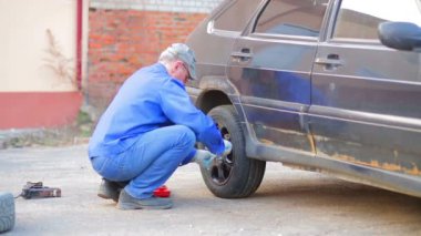 Bir anahtar ile erkek oto tamircisi bir araba tekerleği güvenli